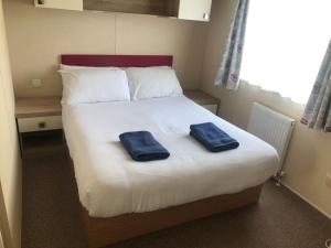 Una cama con dos toallas azules encima. en Cute caravan Whitecliff Bay, en Bembridge