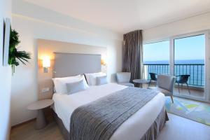 a hotel room with a large bed and a large window at Princess Et Richmond in Menton