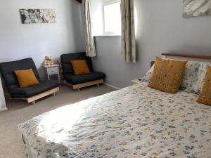 a bedroom with a large bed and two chairs at Cottage in North Somerset in Clevedon