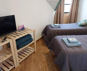 ein Zimmer mit zwei Betten und einem Flachbildfernseher in der Unterkunft Departamentos Cerro Chaltén in El Chalten
