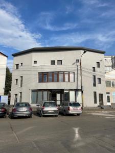 a large building with cars parked in a parking lot at Rooms in Bacău