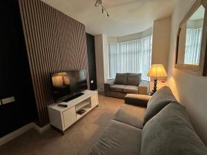 Una sala de estar con un sofá y un televisor de pantalla plana. en 2br Stylish Ormeau Road House, en Belfast