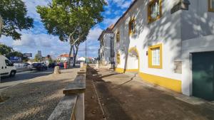 Una calle con un edificio blanco y amarillo y una carretera. en T'Inácia Guest House, en Évora