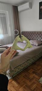 a person making a heart shaped pillow on a bed at Apartman Tajna in Sremčica +6 photos