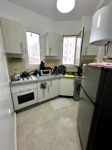 a kitchen with white cabinets and a refrigerator at Appartement cosy à 5 min de la plage Sidi Kacem in Hajreien