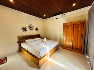 Un dormitorio con una cama y un armario de madera. en Kelapa Villa Mambal, en Mambat 30 fotos más