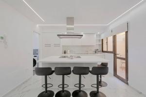 a kitchen with a white counter and stools at Adosado Sara en Fanabe in Adeje