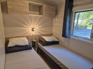 zwei Betten in einem kleinen Zimmer mit Fenster in der Unterkunft Cottage Les 2 Chardon in La Teste-de-Buch