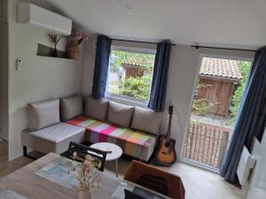 ein Wohnzimmer mit einem Sofa und einer Gitarre in der Unterkunft Cottage Les 2 Chardon in La Teste-de-Buch + 5 Fotos