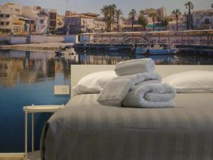 a bed with towels on it next to a body of water at Miramare Luxury Rooms in Scoglitti