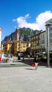 a person walking down a street with a mountain in the background at Ampio monolocale vicino al lungolago di Lecco in Lecco