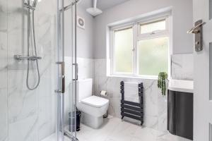 a white bathroom with a toilet and a shower at Inspira Stays - Spacious Modern House in Leicester - Free Parking - Xbox, Table Football & Smart TV in Braunstone