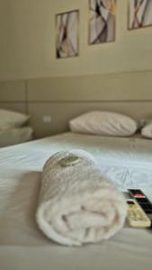 a towel sitting on a bed with two remote controls at GRAN HOTEL in Três Lagoas