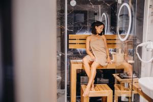 kobieta w sukience siedząca na ławce w łazience w obiekcie Five Seasons Szklarska Poręba w Szklarskiej Porębie