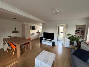a living room with a table and a couch and a kitchen at Woning nabij Eemshaven in Krewerd