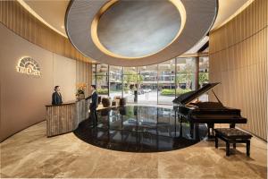 a man standing in front of a piano in a lobby at The Metropole Opera Residence by KayStay in Ho Chi Minh City