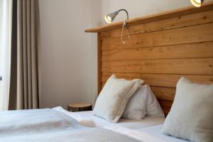 a bedroom with a white bed with a wooden headboard at Heimat Natur Resort in Prägraten