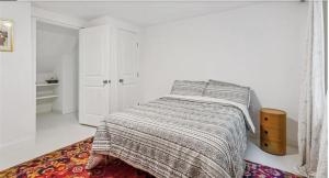 a white bedroom with a bed and a rug at Historic New Orleans in the Treme in New Orleans +2 photos