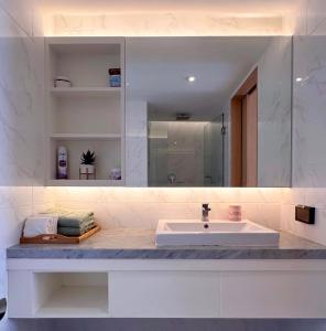 une salle de bain blanche avec un lavabo et un miroir dans l'établissement Aristo-2-805, à Ban Lum Fuang