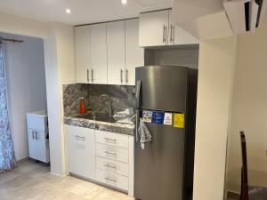 una cocina con nevera de acero inoxidable y armarios blancos en Ricks place, en Guayaquil