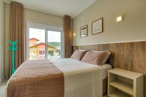 a bedroom with a large bed and a large window at Residencial Casa Flora in Bombinhas