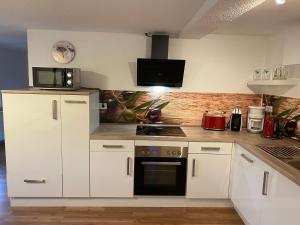 a kitchen with white cabinets and a microwave at Ferienhaus Sonnenterrasse in Gerstenberg +14 photos