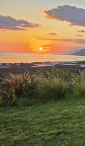 a sunset over a beach with grass and the ocean at Casa di Olive Luxury Secluded Sea View Villa in South Crete in Goúdhouros +51 photos