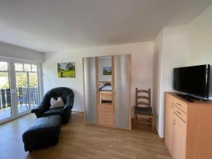 a living room with a television and a chair at Haus Biber - altersgerechtes Ferienhaus am Niederrhein - in Sonsbeck