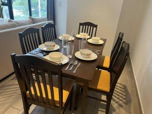 a dining room table with four chairs and a wooden table with dishes on it at Apartamento entero de 3 habitaciones con camas Queen en zona 10 in Guatemala