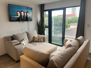 a living room with a couch and a flat screen tv at Apartamento entero de 3 habitaciones con camas Queen en zona 10 in Guatemala