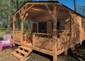 a wooden cabin with a pink chair and a table at Camping la Croix du Sud in Saint-Tropez