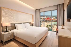 a bedroom with a white bed and a large window at Shinhwa Jeju Shinhwa World Hotels in Seogwipo