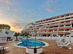 アデへにあるApartment in Ocean Park, Costa Adeje, Tenerifeのスイミングプールと椅子付きの大きなアパートメントです。