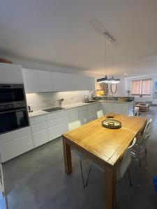 a kitchen with a wooden table and white cabinets at Soleil de Sète, maison coquette en cœur de ville in Sète +22 photos