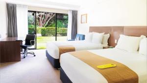 a hotel room with two beds and a desk at Holiday Inn Auckland Airport by IHG in Auckland
