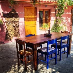 a wooden table and chairs in front of a house at -Giardino- Vakantiehuis tussen de olijvenbomen in Donori