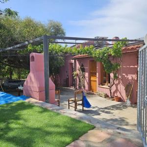 a backyard with a pink house with a fence at -Giardino- Vakantiehuis tussen de olijvenbomen in Donori