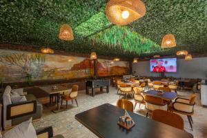 IsioloIman Hotel的餐厅拥有绿色的天花板,配有桌椅