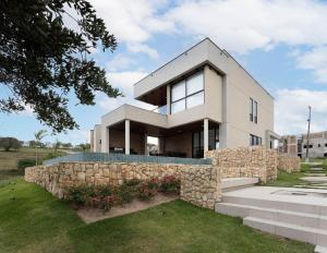 una grande casa bianca con un muro di pietra di CoHost Casa Conceito Raiz da Serra IV a Gravatá