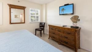ein Schlafzimmer mit einem Bett und einer Kommode mit Spiegel in der Unterkunft Modern and Coastal Ocean Pointe 2307 in Key Largo