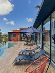 a patio with chairs and an umbrella next to a pool at La Maison Loosaï -Amφur- sans TV in Itacaré +13 photos