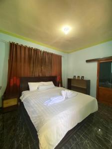 a bedroom with a large bed with white sheets at Kurnia Family Homestay & Restaurant! in Huu