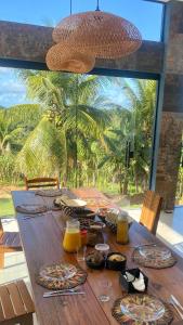 a wooden table with food on it with a large window at La Maison Loosaï -Amφur- sans TV in Itacaré