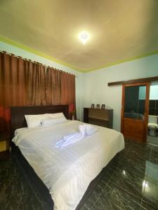 a bedroom with a large white bed with towels on it at Kurnia Family Homestay & Restaurant! in Huu +14 photos