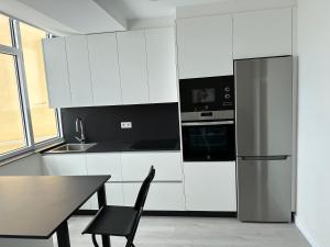 a kitchen with white cabinets and a black refrigerator at Malteses in A Guarda