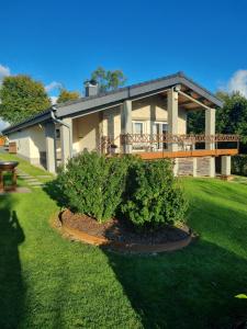 a large house with a deck and a yard at LAC ACHETTE AU LAC in Butgenbach