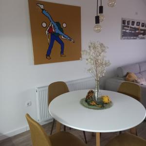 a white dining room table with a vase of flowers at Apartman Prodan in Sombor