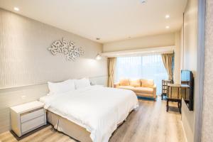 una camera da letto con un grande letto bianco e una sedia di Walker Hotel. Ximen a Taipei