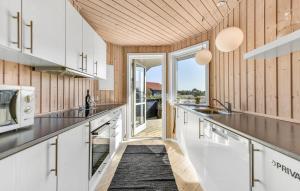 a kitchen with white cabinets and wooden walls at Gorgeous Home In Ulfborg With Kitchen in Ulfborg