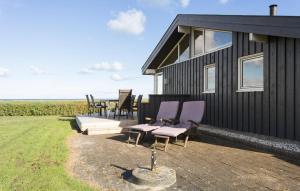 a black house with purple chairs and a patio at 4 Bedroom Lovely Home In Sæby in Sæby